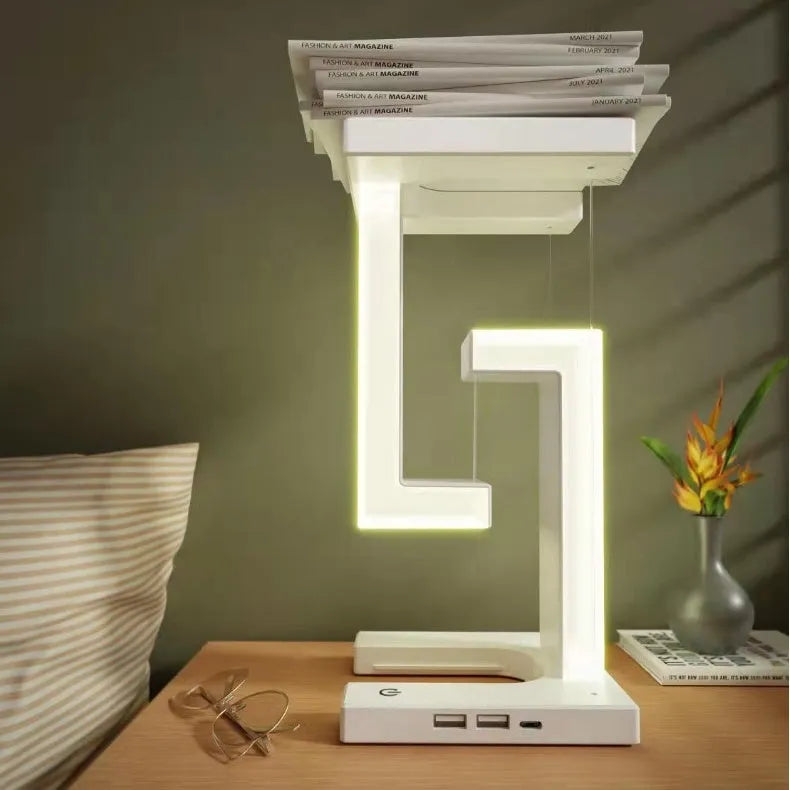 White magnetic suspension table lamp with wireless charging base, floating shade, and foldable bracket on a desk