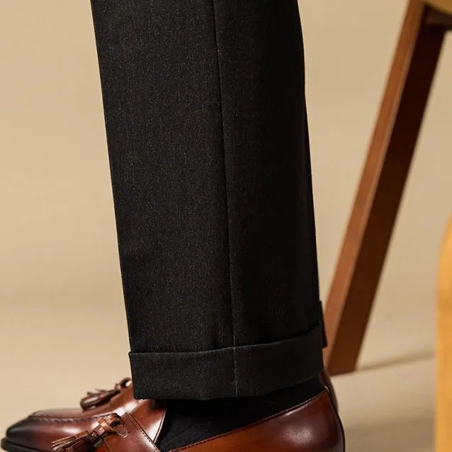 Men's black polished leather tassel loafers with rubber sole, shown from the side.