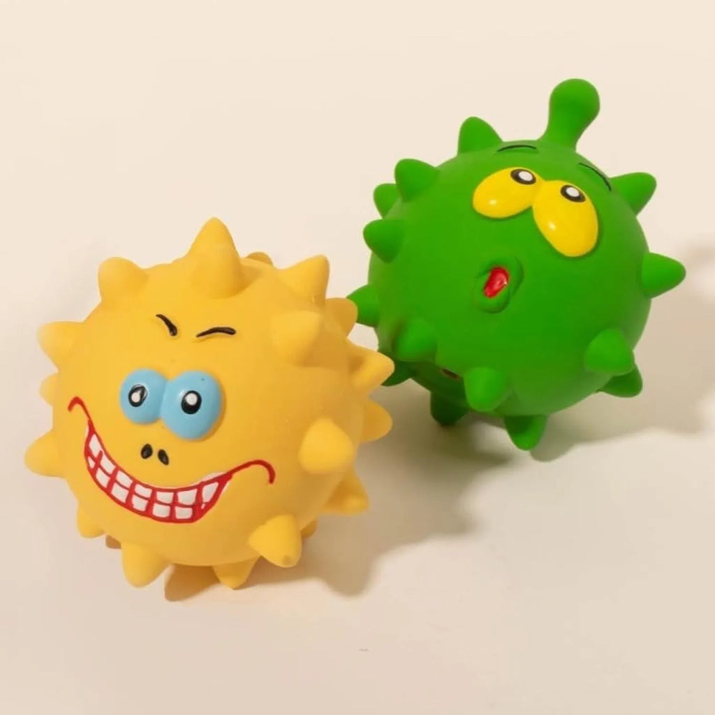 Set of four colourful latex squeaky dog balls with cute faces on a textured surface.