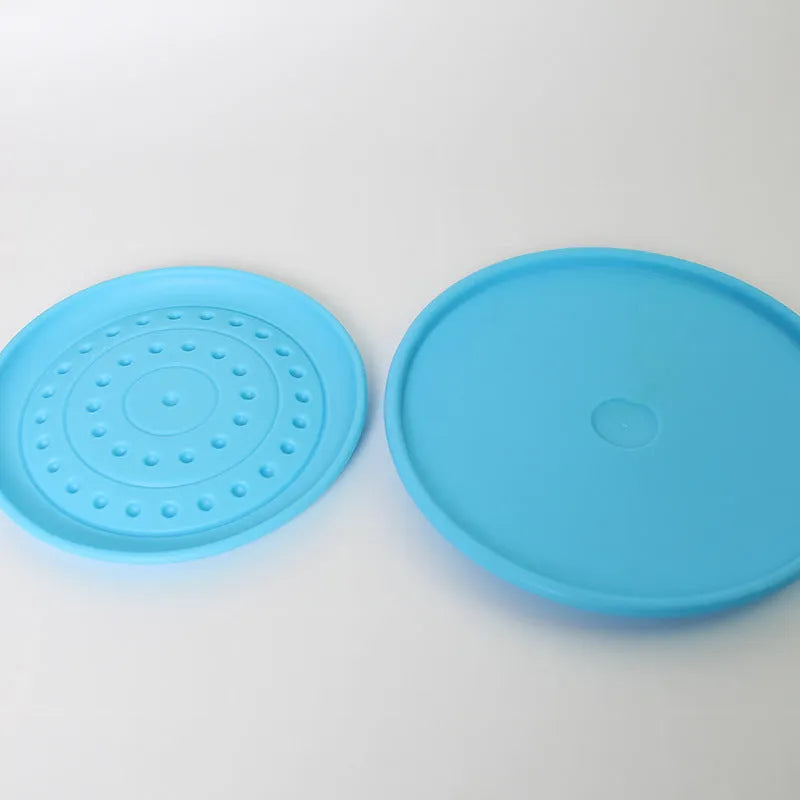 Plastic dog flying disc toy in green, shown on grass for scale