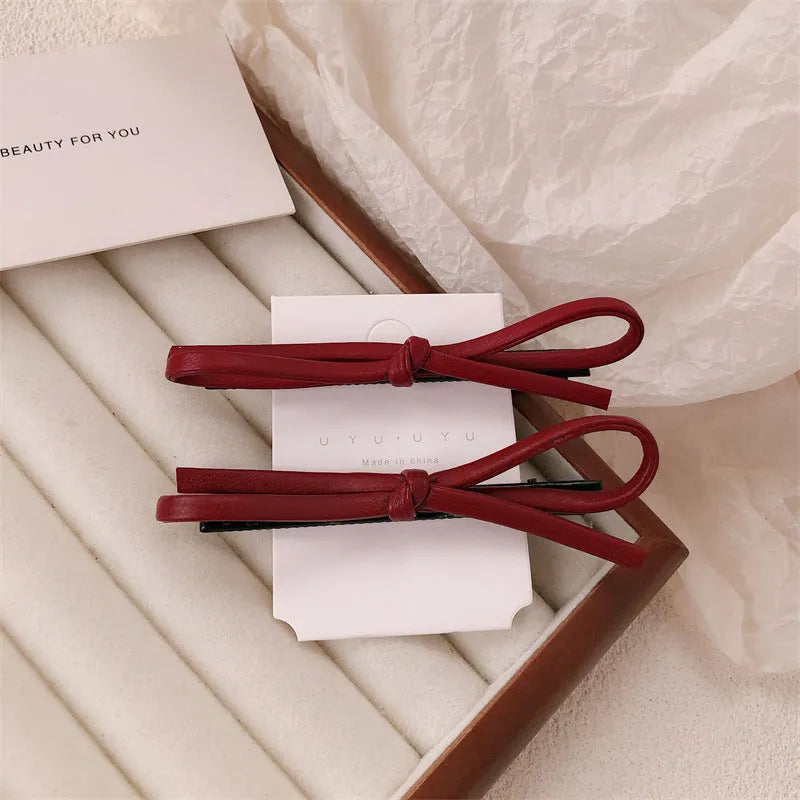 Wine red genuine leather bow hair barrette with a 6cm long metal clip on a white background.