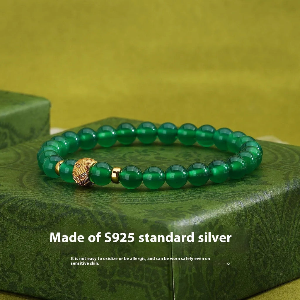 Close-up of a women's bracelet with a green agate stone on a two-tone silver and gold-plated chain.