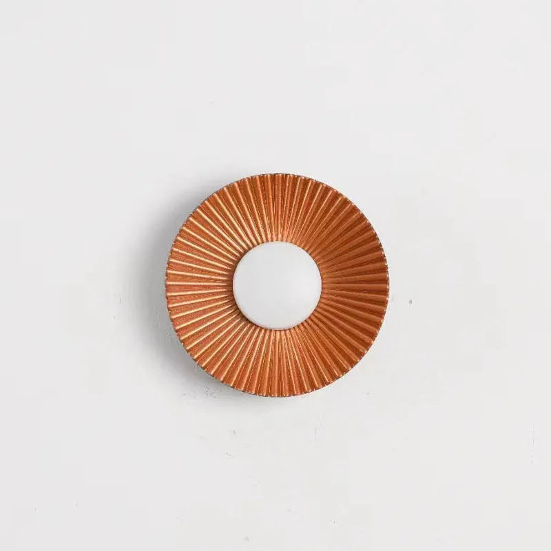 Round aluminium wall lamp in an outer white and inner gold colour combination, mounted on a wall.