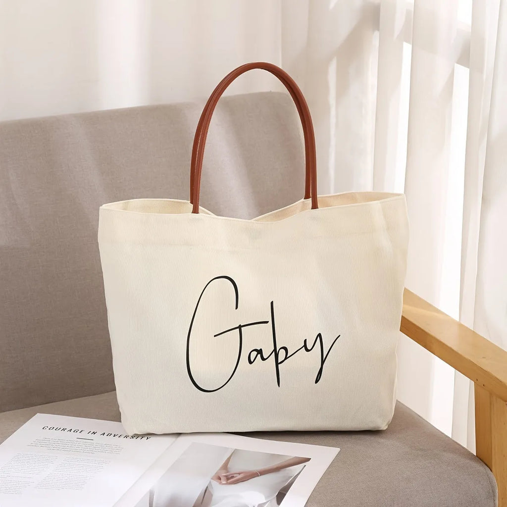 Beige white canvas tote bag with detachable crossbody strap, side bottle pockets, and a front zipped compartment.