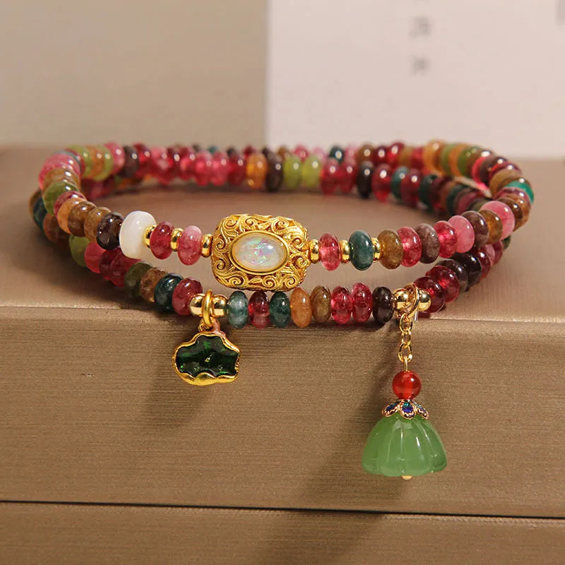 Rainbow tourmaline abacus beads double ring bracelet with lotus seedpod and flower shapes, on white background