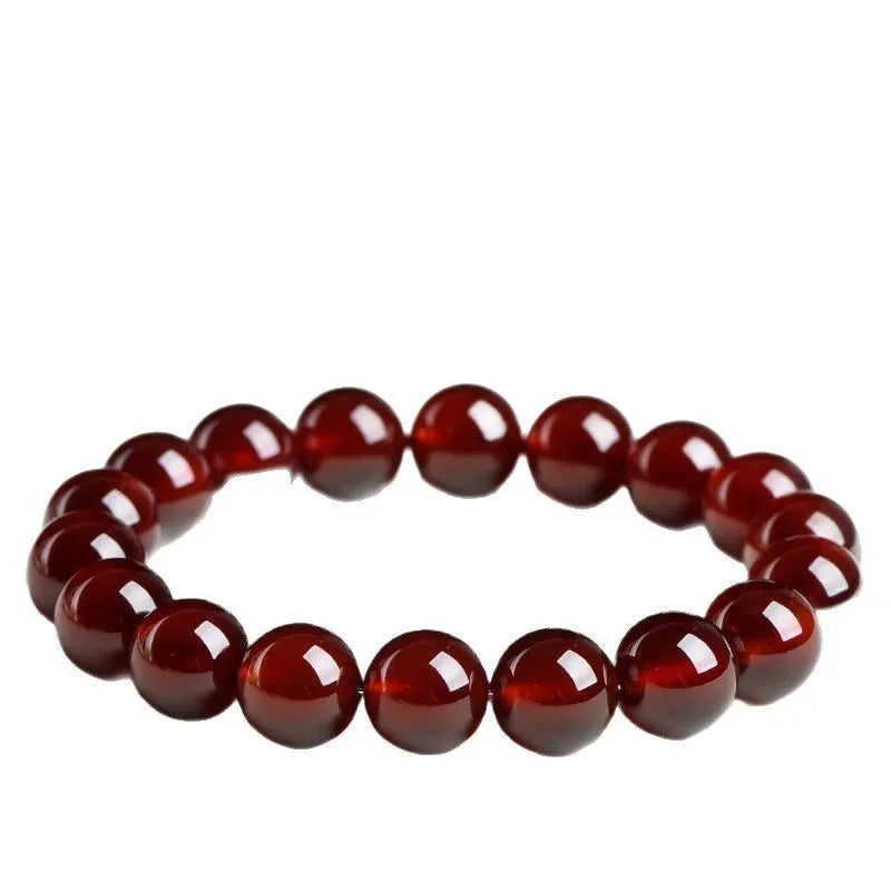Close-up of a natural orange red garnet bead bracelet with a metal Ruyi charm on a wrist.
