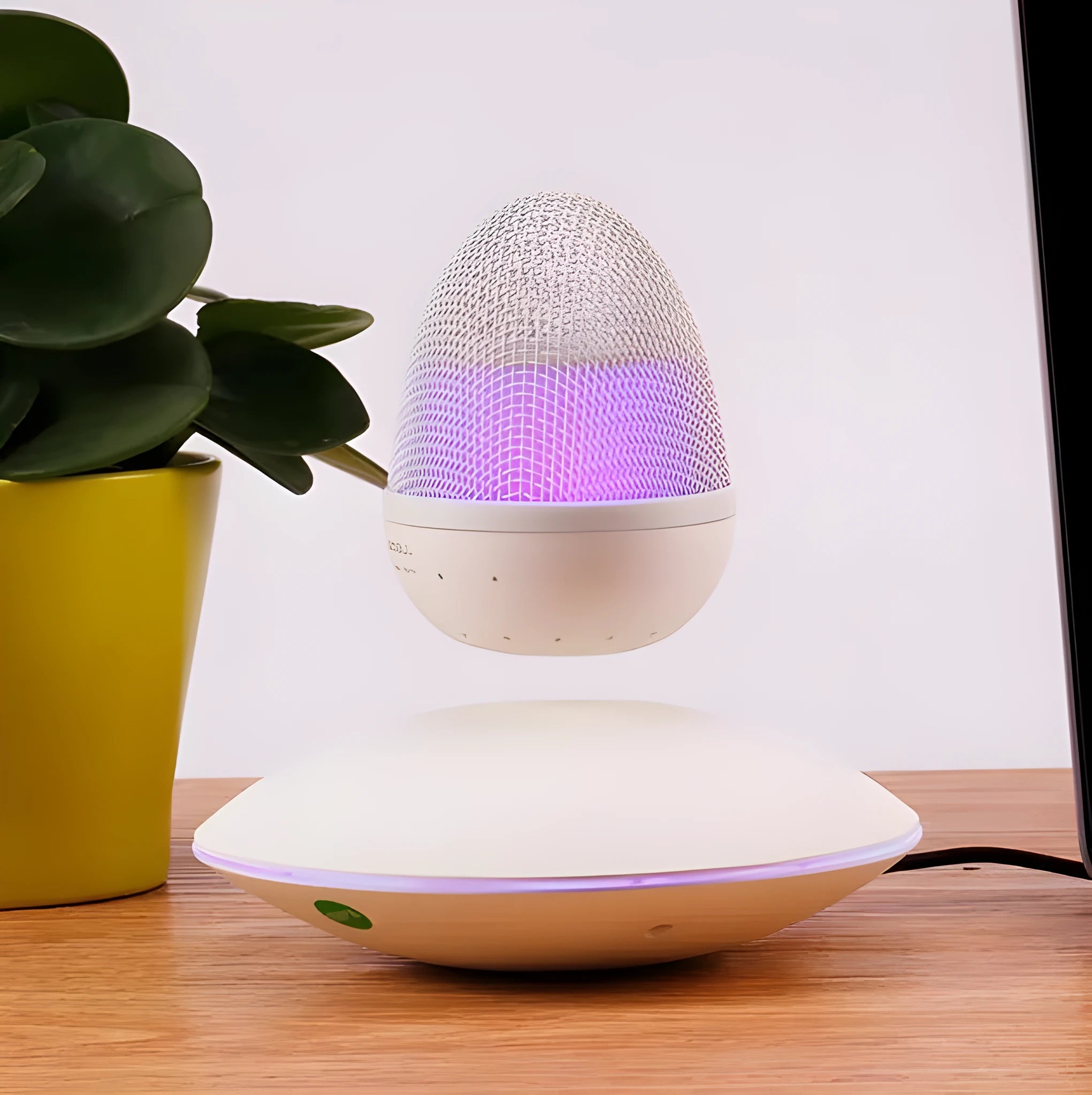 Levitating floating speaker with magnetic suspension, cast FRP body, black colour, hovering above base on a desk