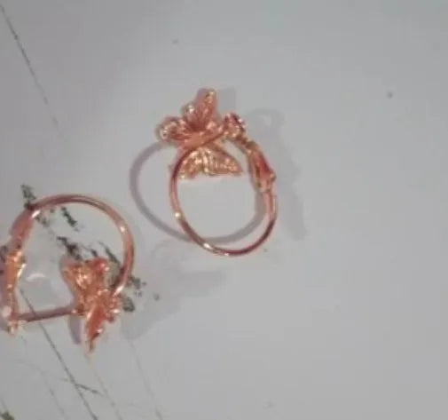 Gold copper alloy stud earrings with butterfly and bow design on white background