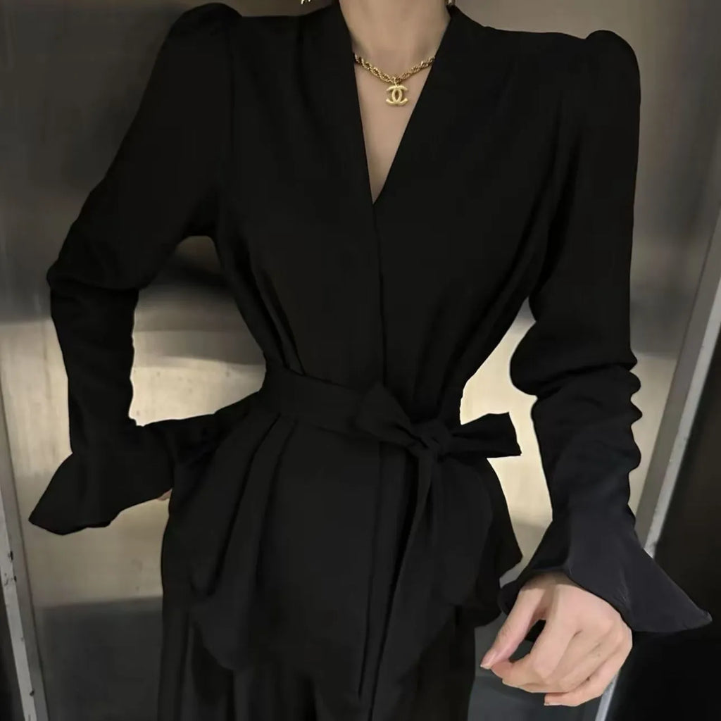 Woman wearing a black tied shirt with a French-style collar and long bell sleeves.