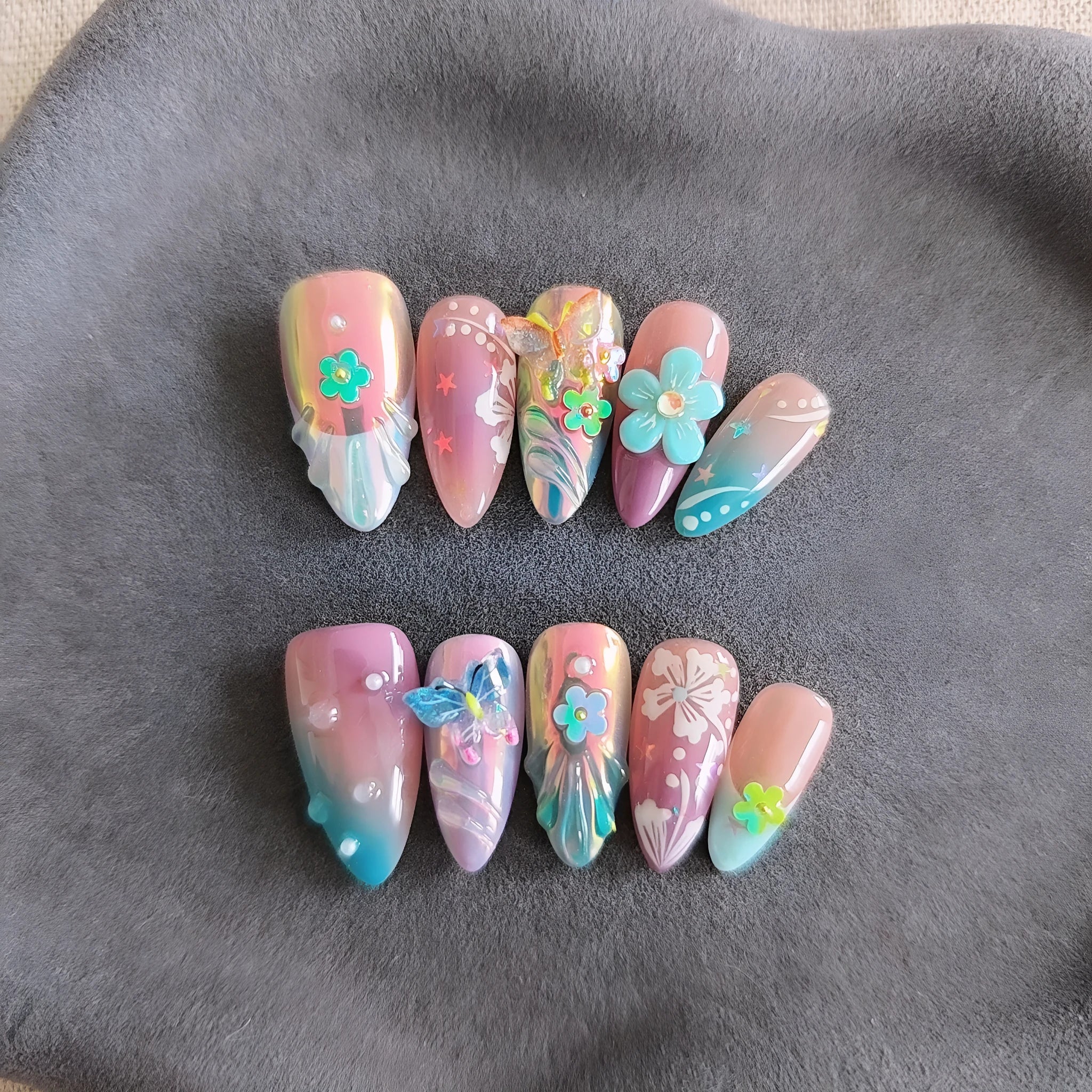 Handmade colourful embossed flower and butterfly nail art charms on a manicure set.