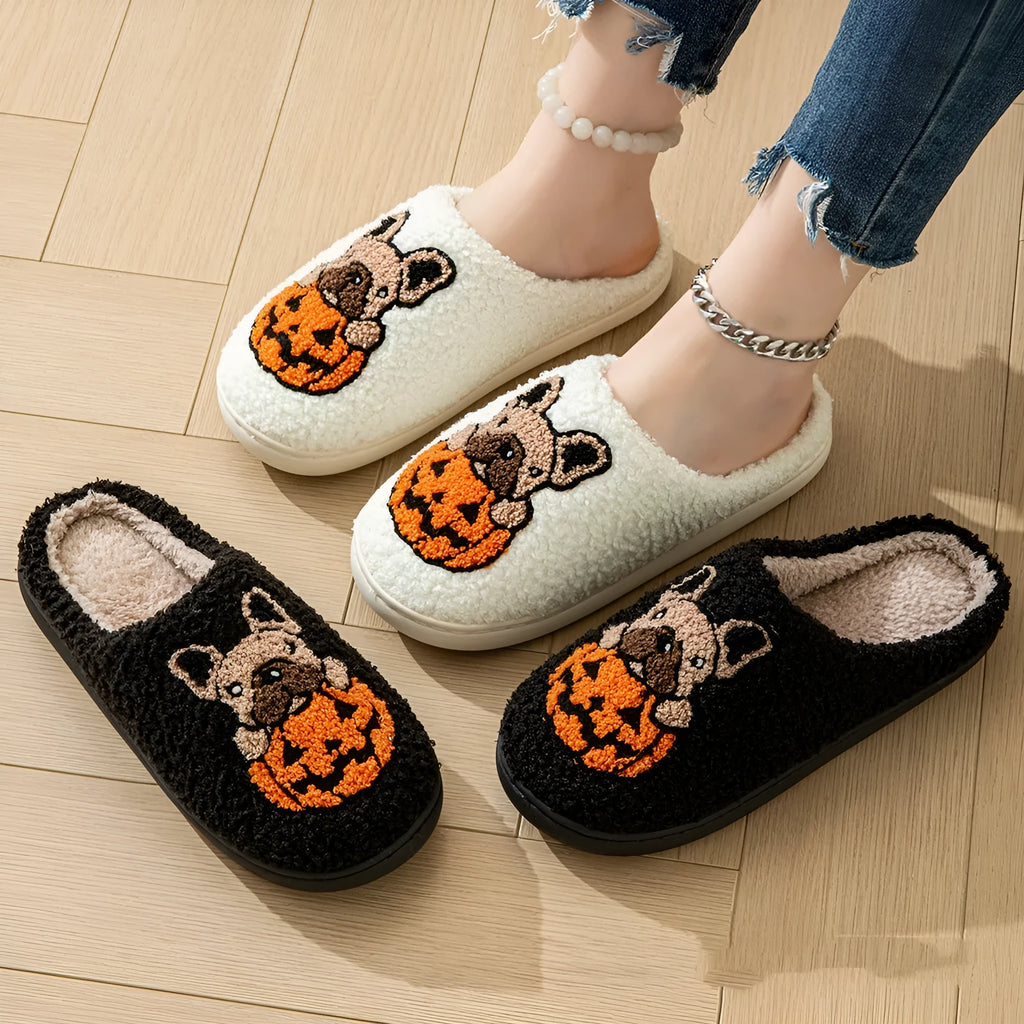 Pair of black plush house slippers with orange pumpkin print and a textured non-slip rubber sole.