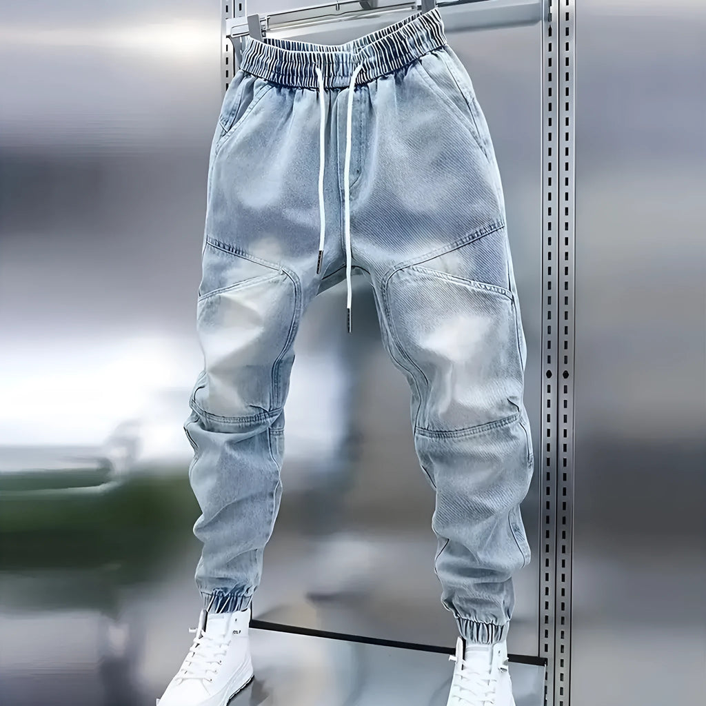 Men's light blue micro-elastic cotton denim pencil trousers with drawstring waist and elastic ankle bands on a model.