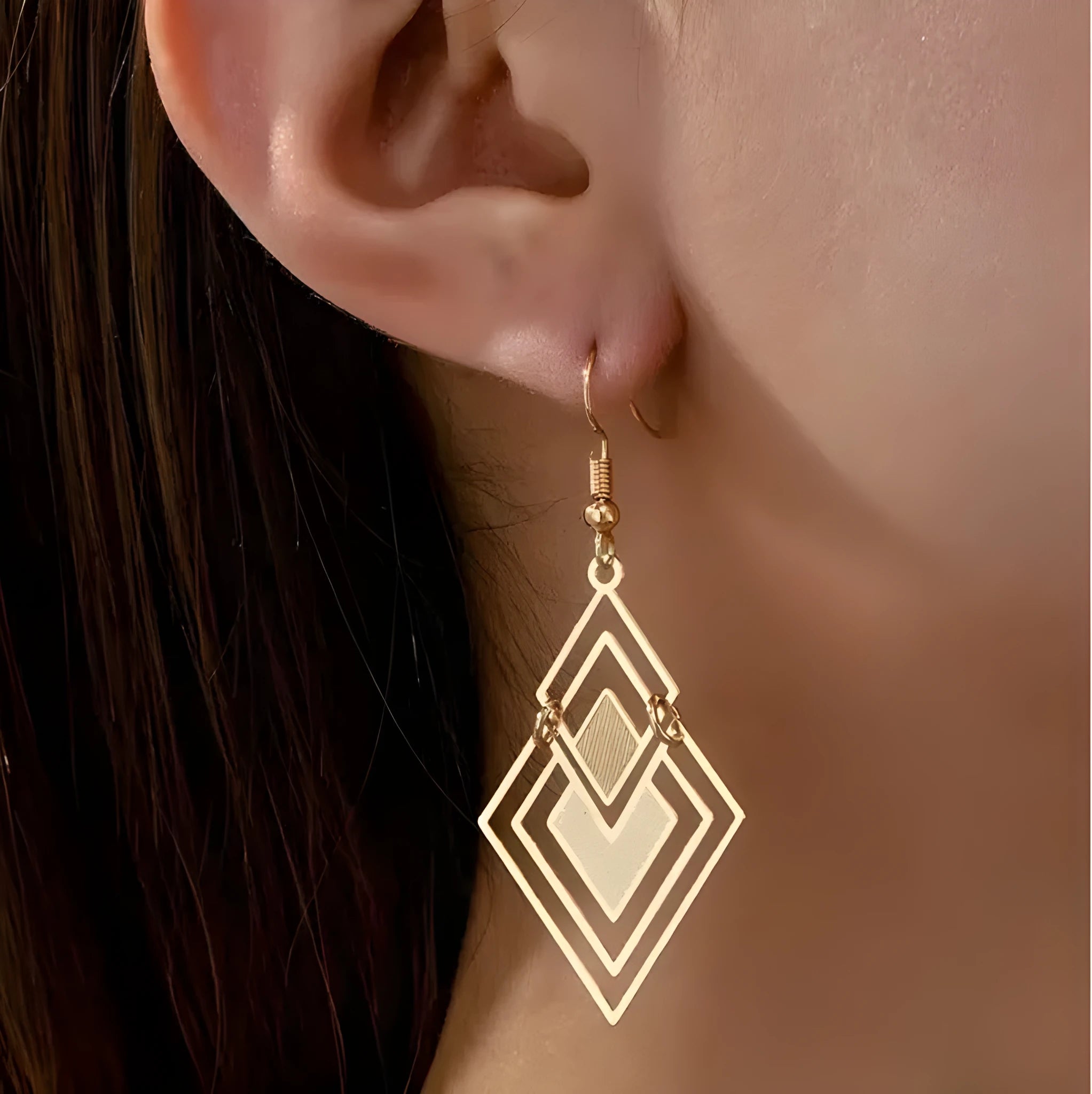 Gold rhombus hollow stud earrings with diamond shape on a light background