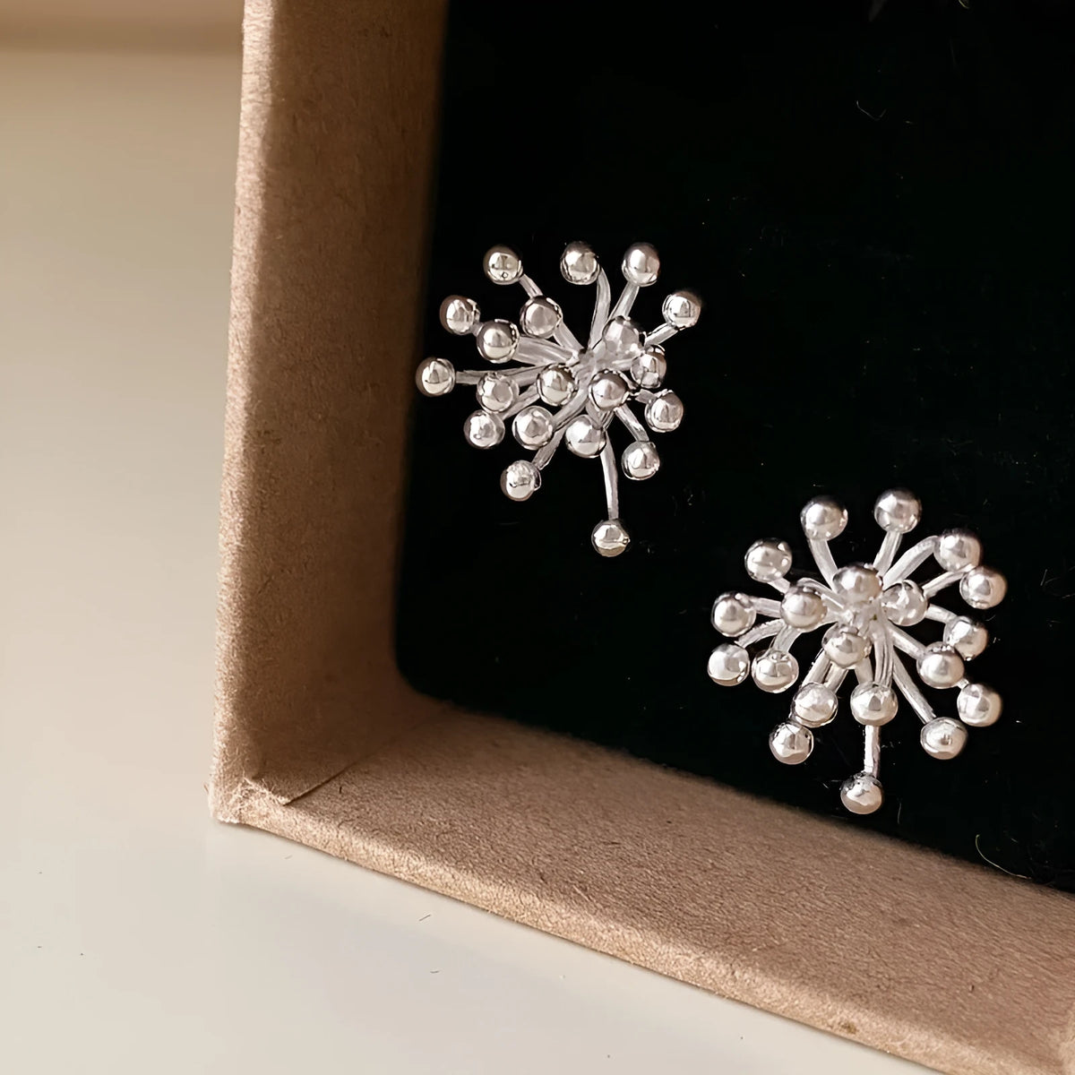Women's silver needle stud earrings with electroplated dandelion fireworks geometric design on white background