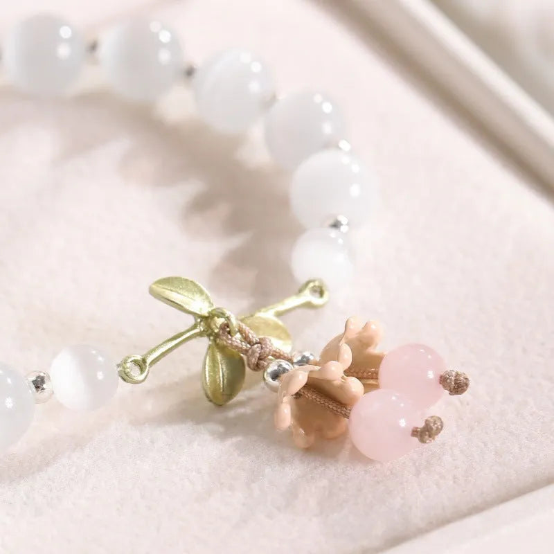 Close-up of a women's opal cat's eye stone beaded bracelet with diamond-shaped beads on a wrist.