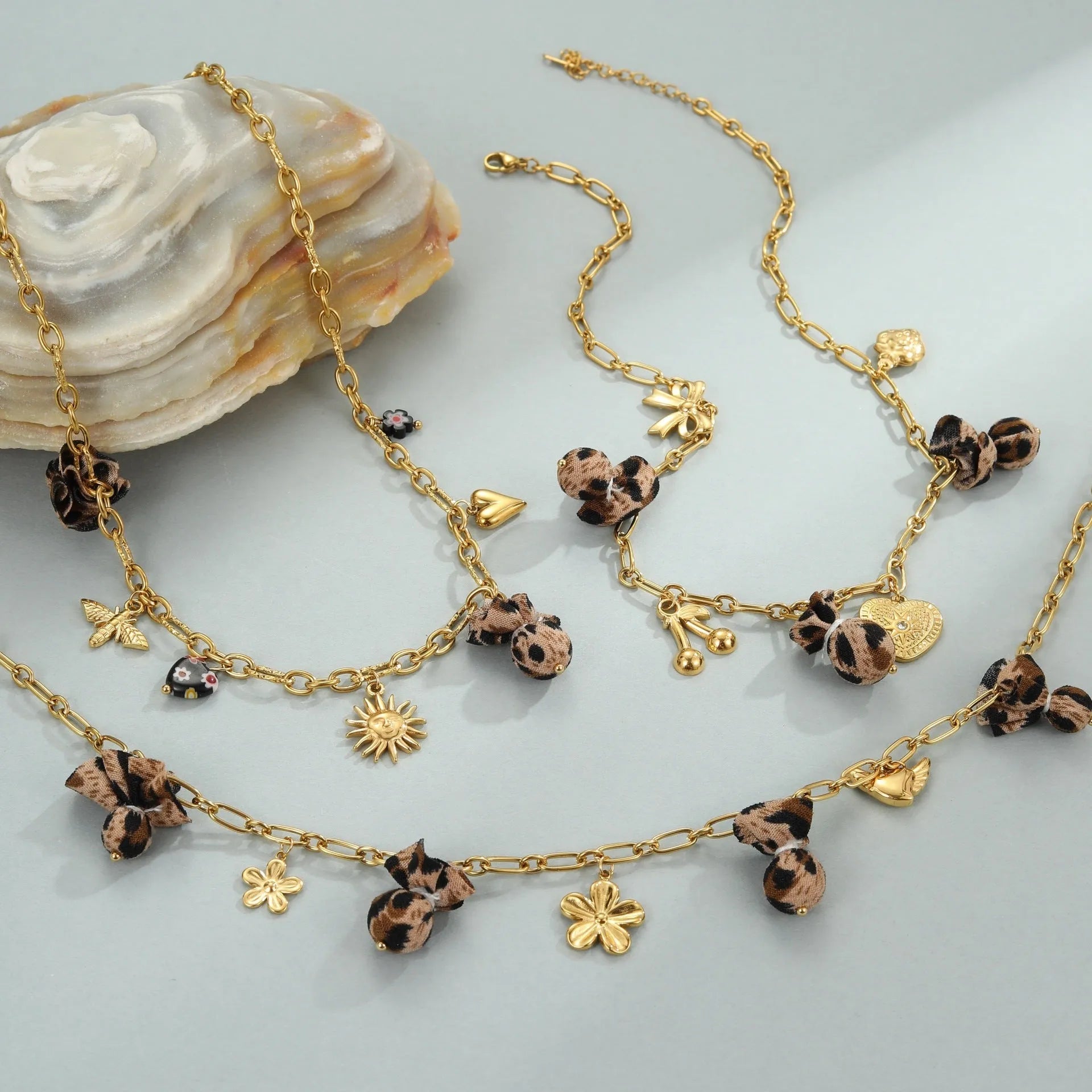 Stainless steel necklace with a geometric leopard pendant and heart and flower accents on an adjustable chain.