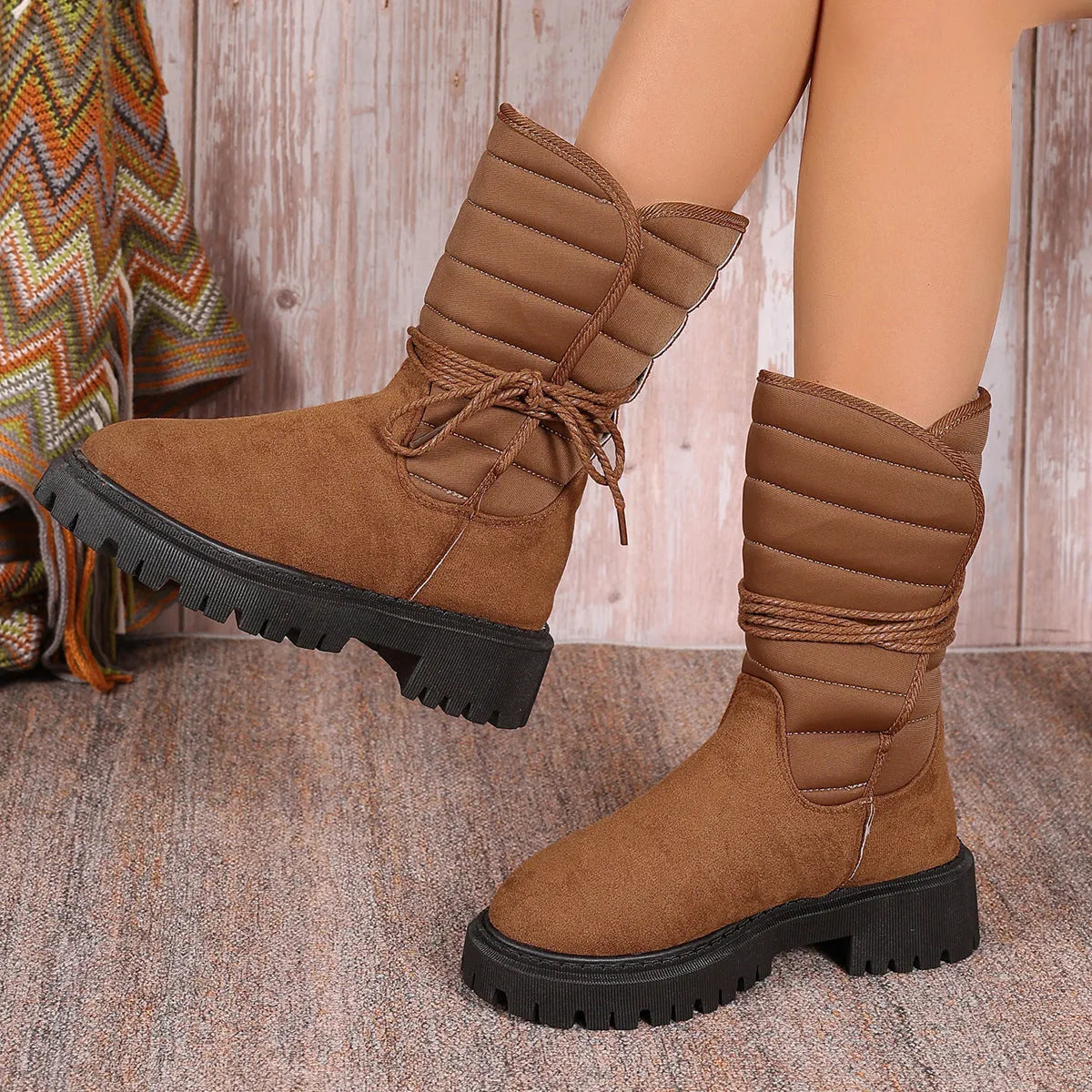 A pair of women's chunky heel snow boots in suede with a lace-up front and fleece lining, shown in black.