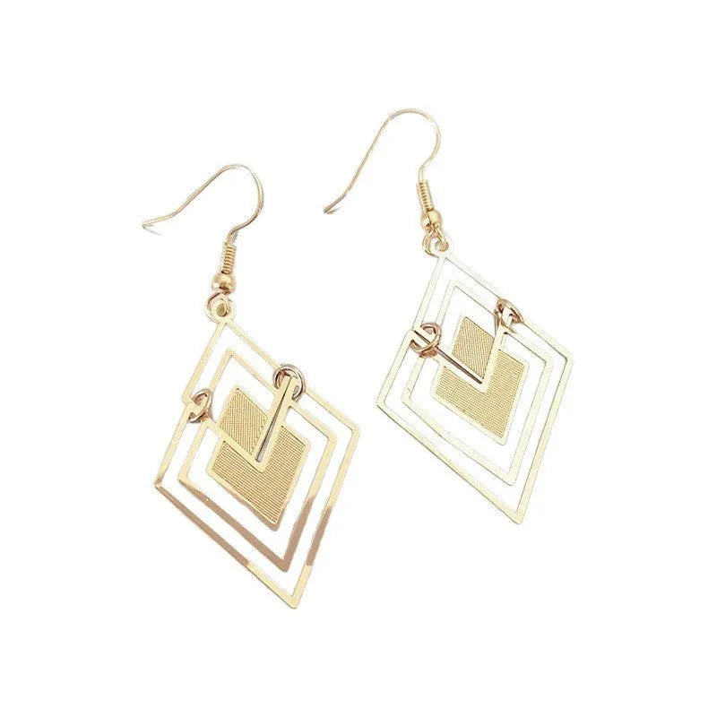 Gold rhombus hollow stud earrings with diamond shape on a light background