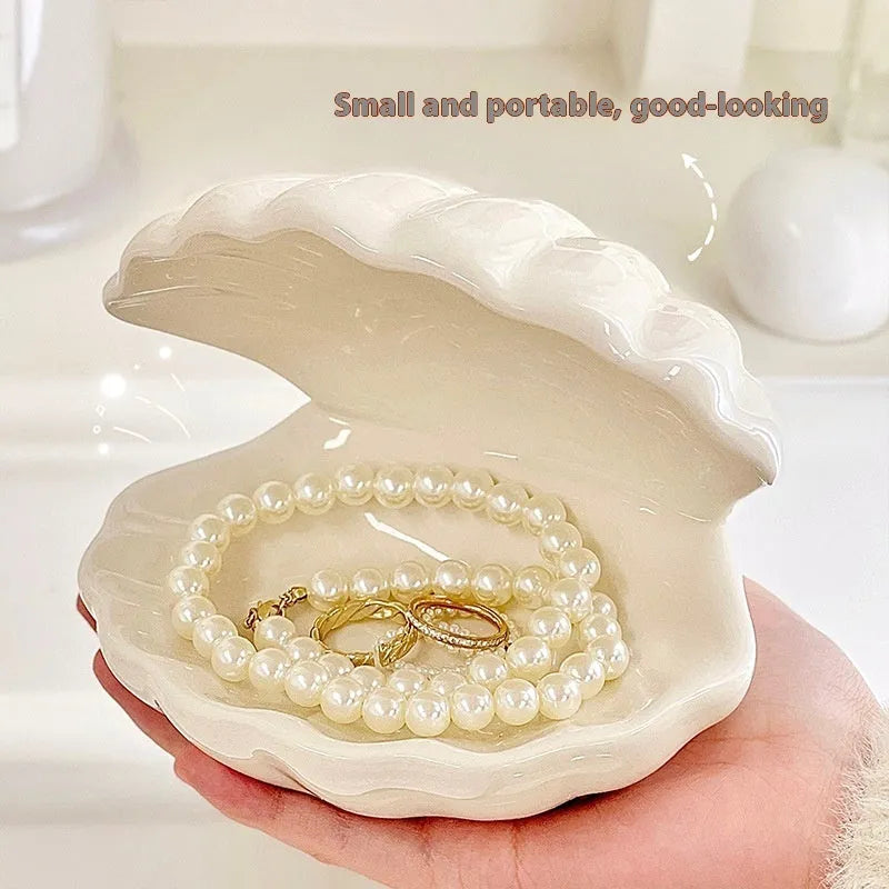 White and pink porcelain shell-shaped tray with integrated yellow LED night light on a wooden table.