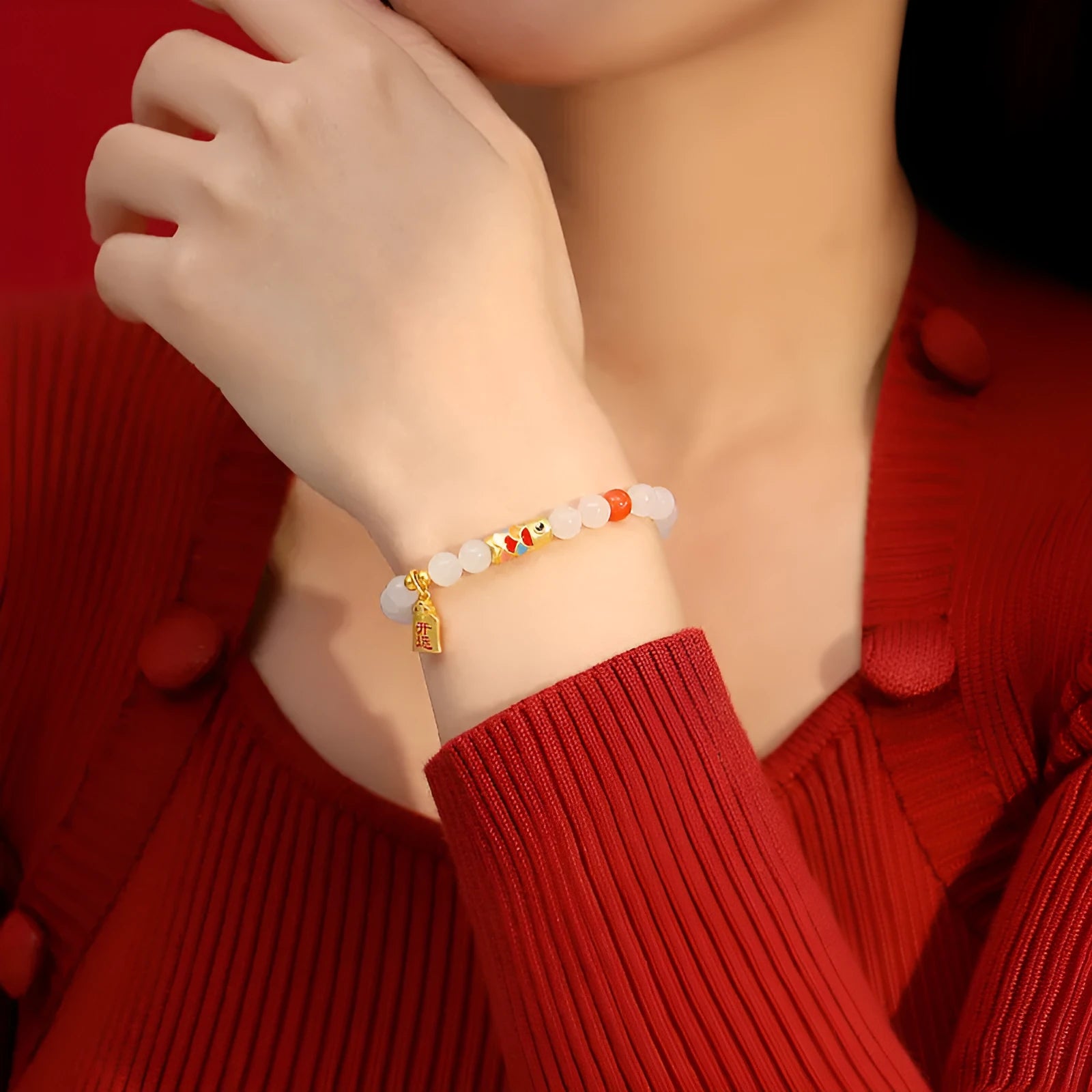 Close-up of a sterling silver bracelet with a blue and orange cold enamel koi fish charm set with Hetian jade.