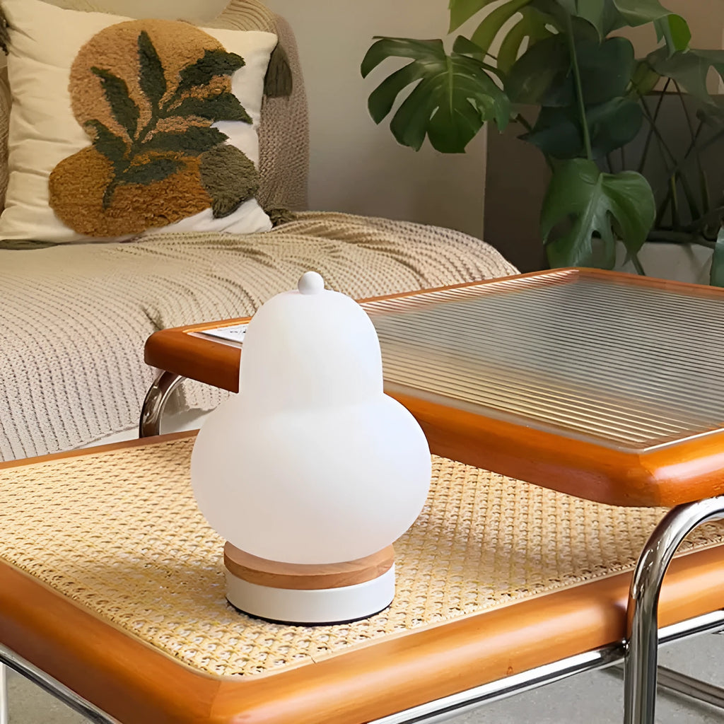 White pear-shaped rechargeable touch LED table lamp with PE shade on a wooden bedside table