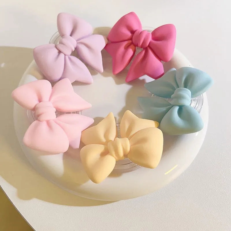 Bow bracket plastic mobile phone stand for lazy binge-watching, available in pink, purple, rose red, yellow, and blue.