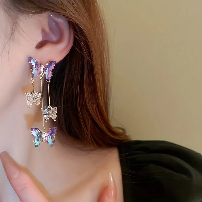Silver Needle Blue Purple butterfly and crystal flower tassel drop earrings on a white background.