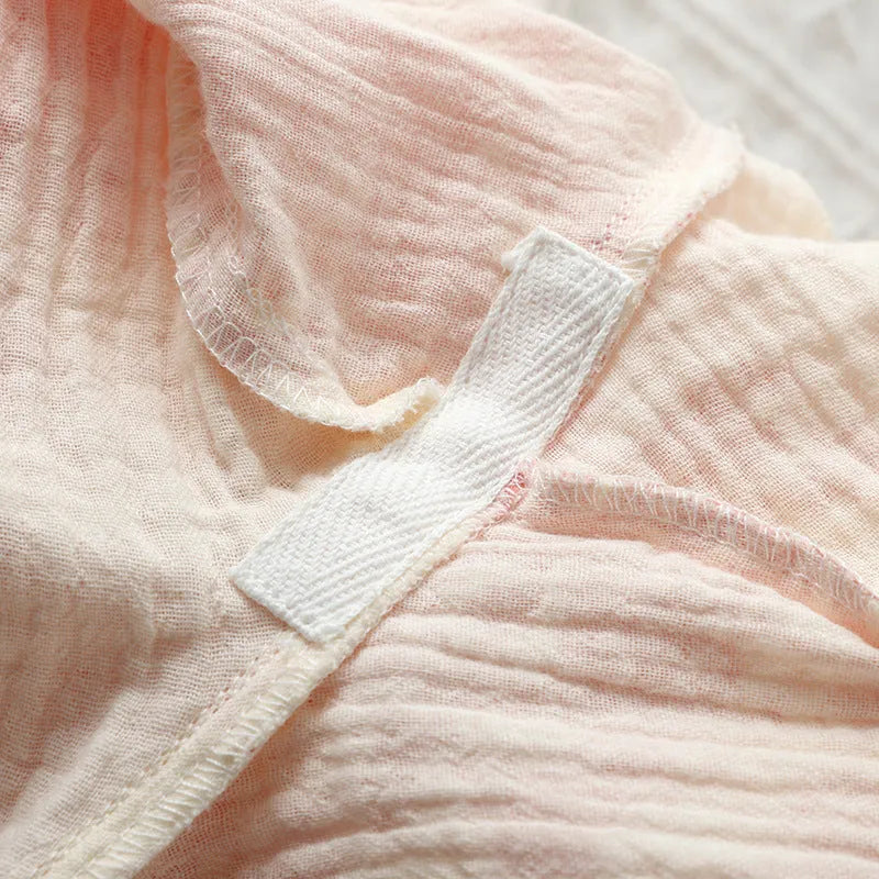 Women's pink cotton gauze lounge suit set with long sleeves and elastic waist trousers laid flat.