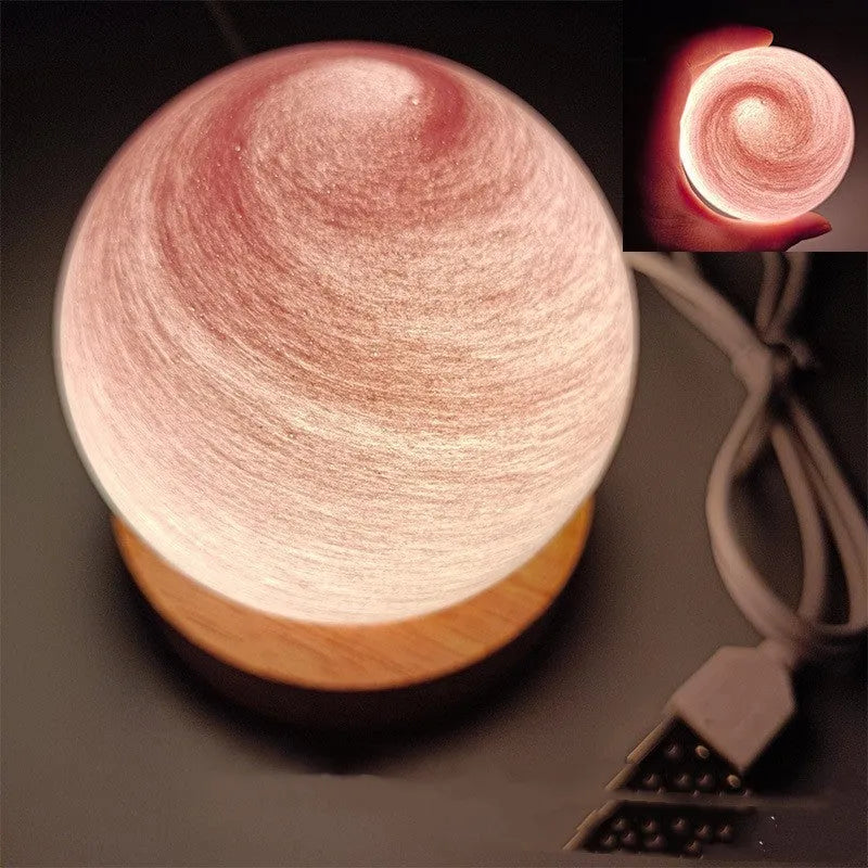 Planet-shaped USB night light on its base with soft multi-colour glow