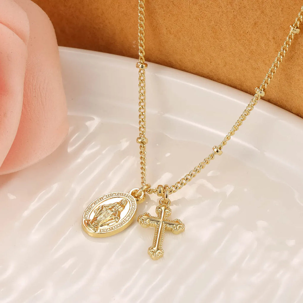 Geometric gold cross Virgin Mary pendant necklace with a simple design on a chain.
