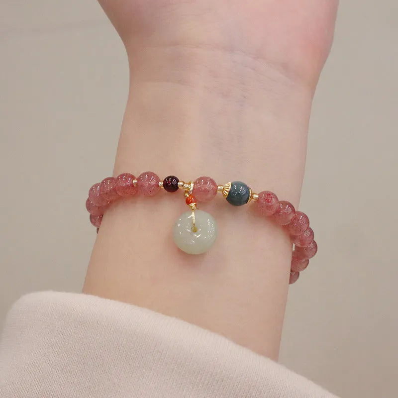 Women's strawberry quartz bracelet with geometric stones, purse charm and lucky bagg charm on wrist