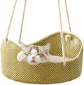 Green rattan cat hammock with metal hooks hanging from a shelf