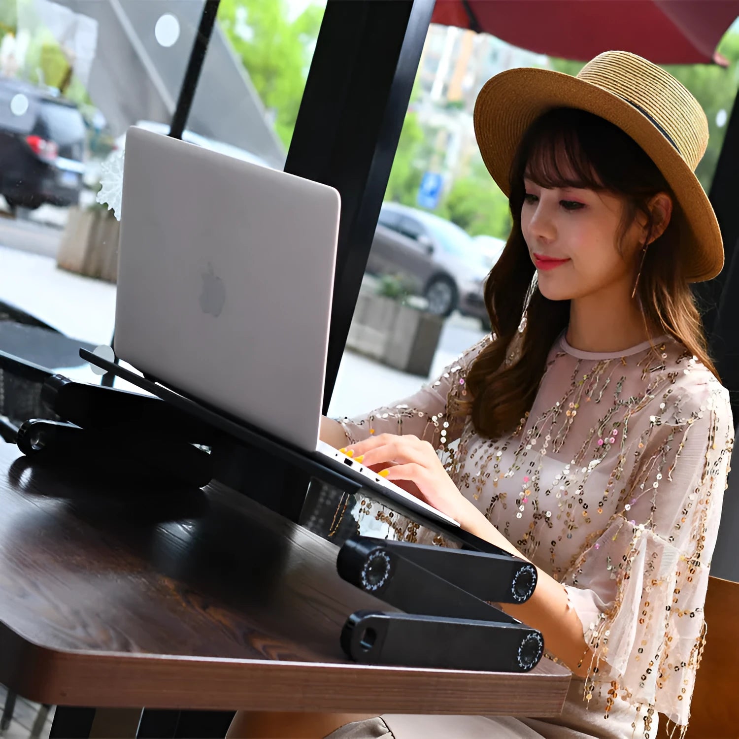 Red folding metal bed desk with cooling holes and a laptop placed on it.