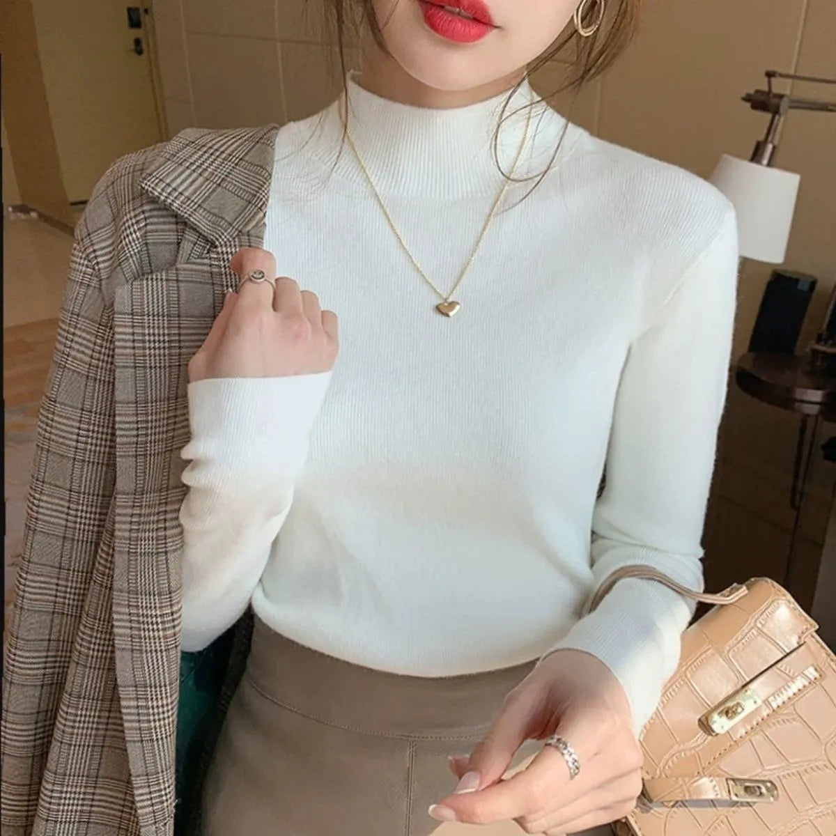 Slim fit apricot coloured viscose knitted long sleeve pullover shirt on a hanger.