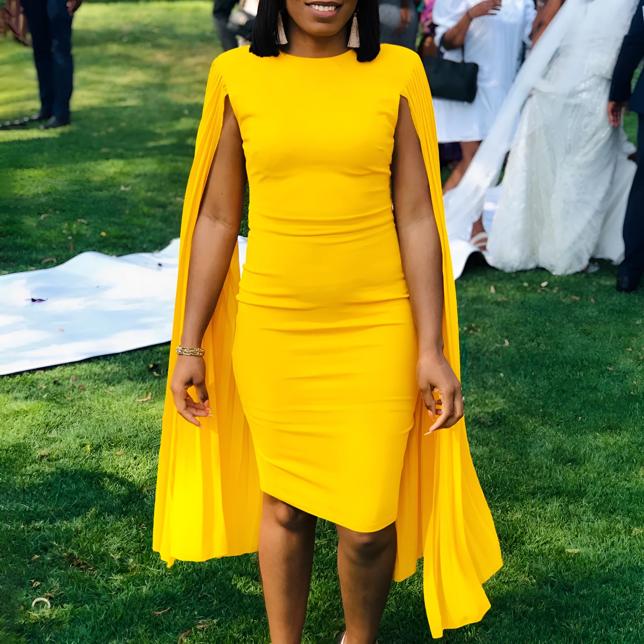 A woman wearing a long sleeve, high-waist pleated evening gown in a solid colour, showcasing the floor-length skirt and round neckline.