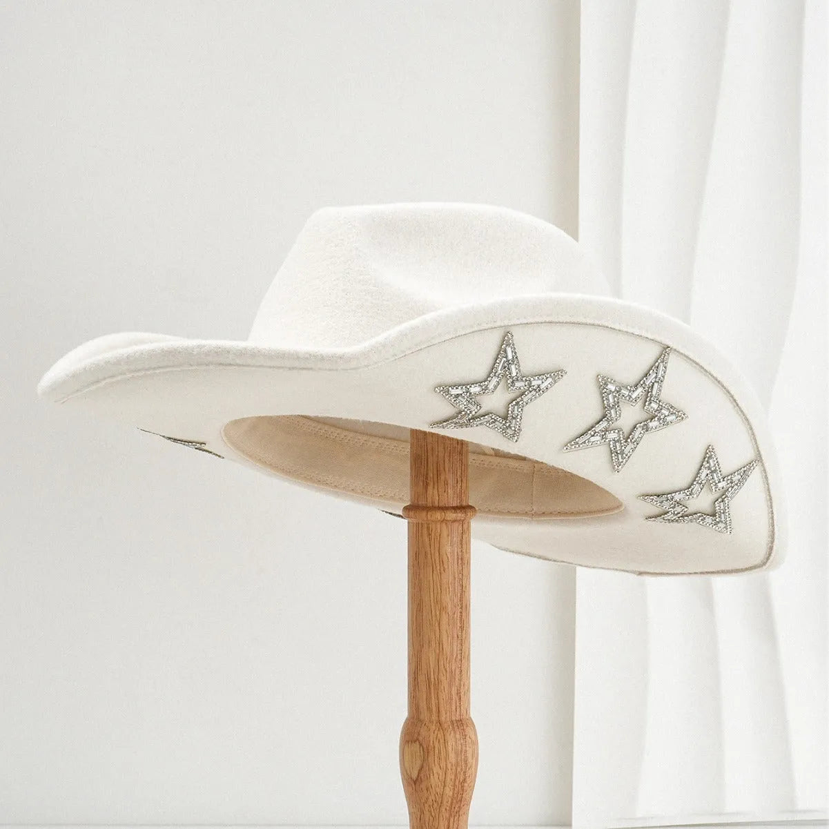 Beige woolen felt Western top hat with a conical crown and a decorative hexagonal star on the front.