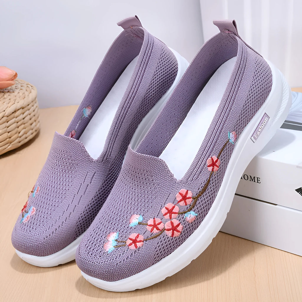 Women's embroidered floral flat pump in woven fabric with a low heel and round toe.