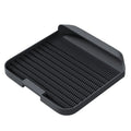 Large black cat litter pedal mat with slanted design next to a litter box.
