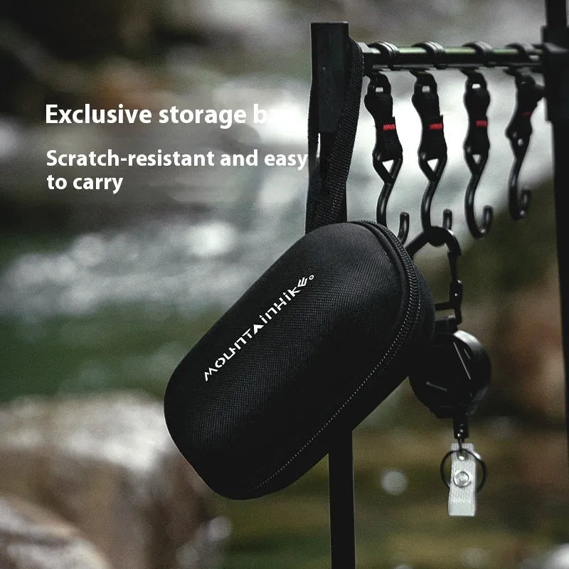 Black hexagon-shaped foldable alloy alcohol camping stove on a wooden surface.
