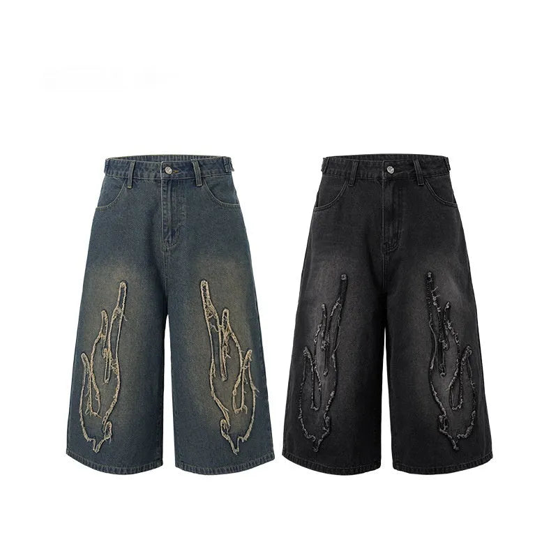 Men's black denim shorts with flame embroidery and a cropped patch on the leg.