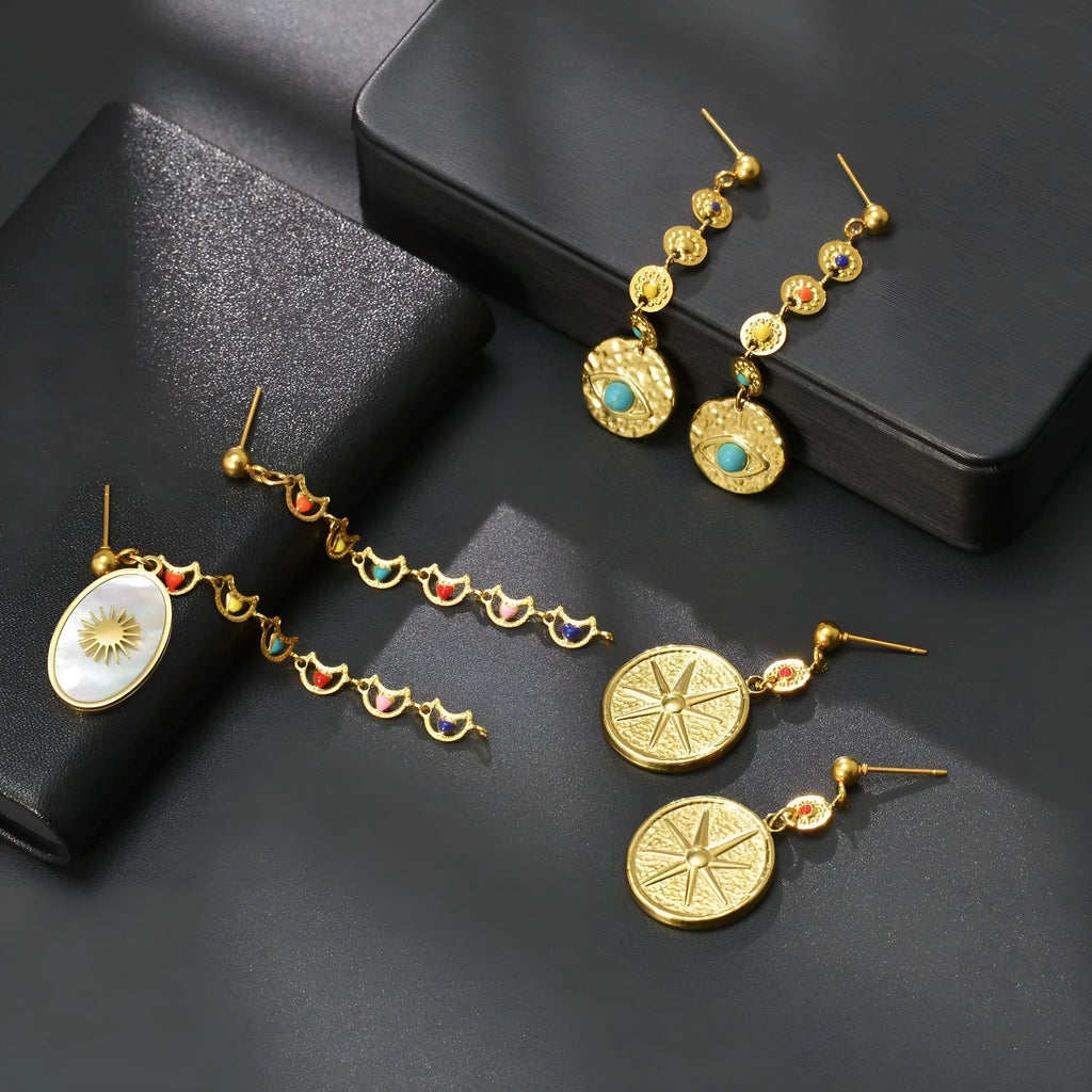 Three geometric stainless steel earrings showing star, eye and shell sun designs
