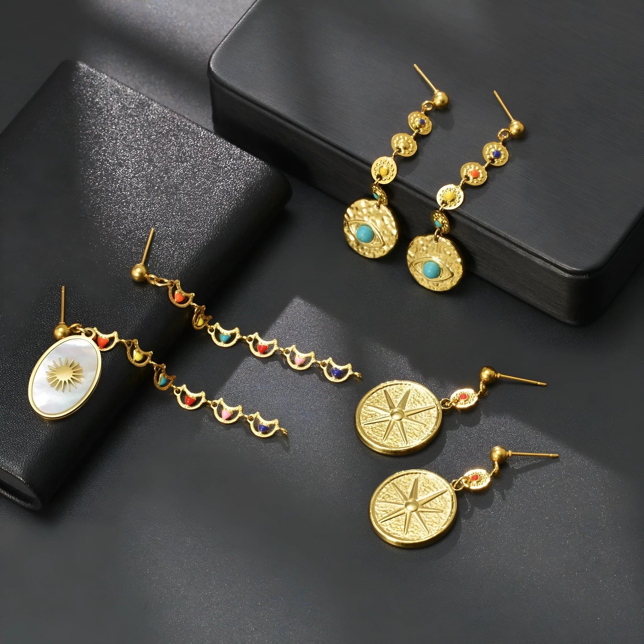 Three geometric stainless steel earrings showing star, eye and shell sun designs