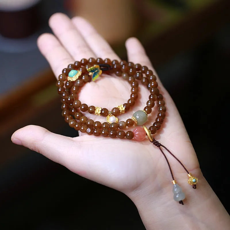 Brown Hetian Jade three-ring bracelet with butterfly and gourd charms on a wrist.
