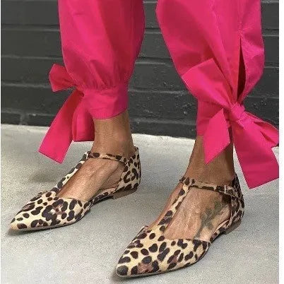 Leopard print women's pumps with pointed toe, cross shoulder straps, and a short chunky low heel.
