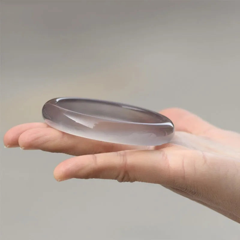 Dark gray iced chalcedony agate bracelet with circle, ring and line elements on neutral background