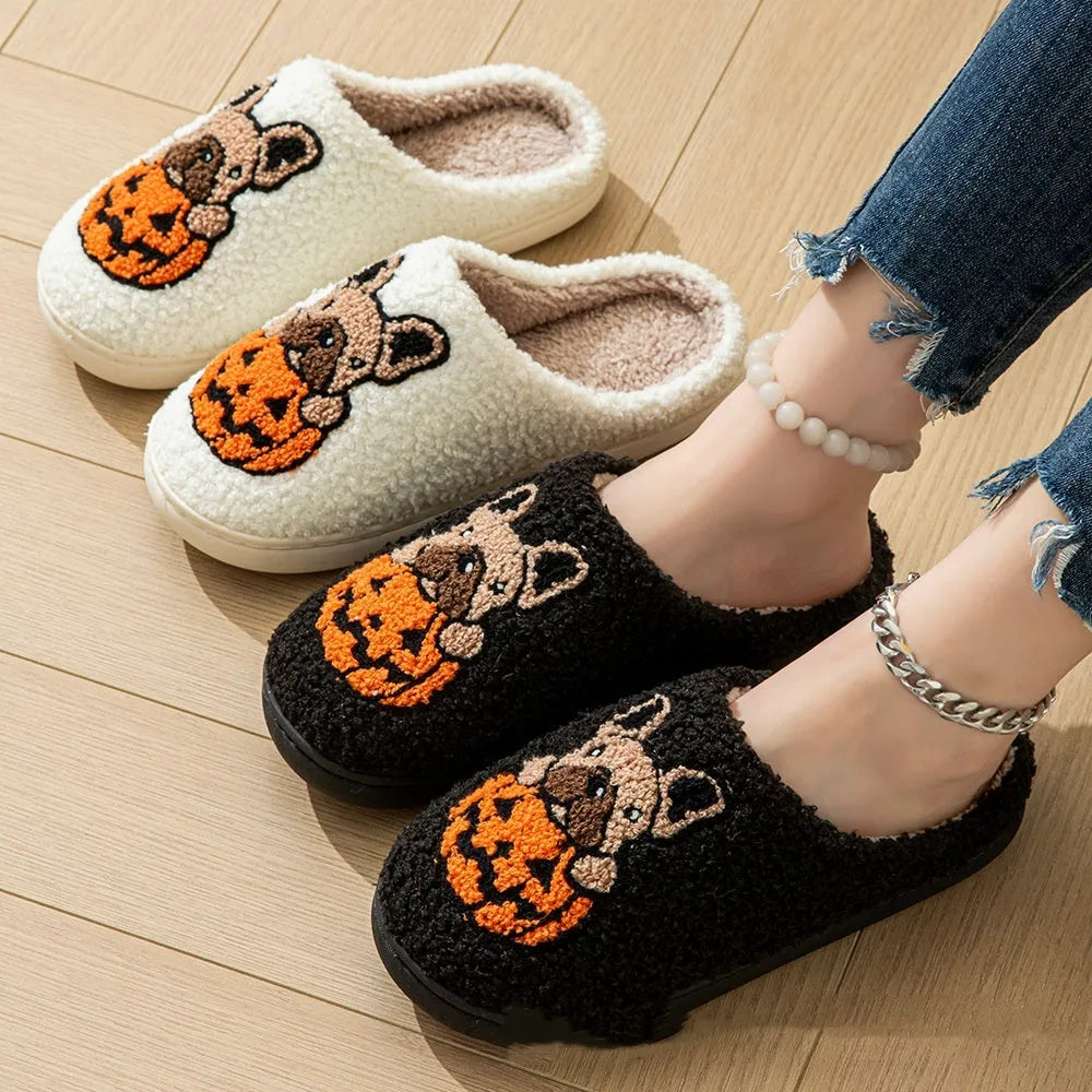 Pair of black plush house slippers with orange pumpkin print and a textured non-slip rubber sole.