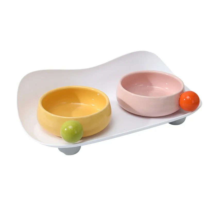 Pink elevated ceramic double bowl set for cat food and water on a non-slip base.