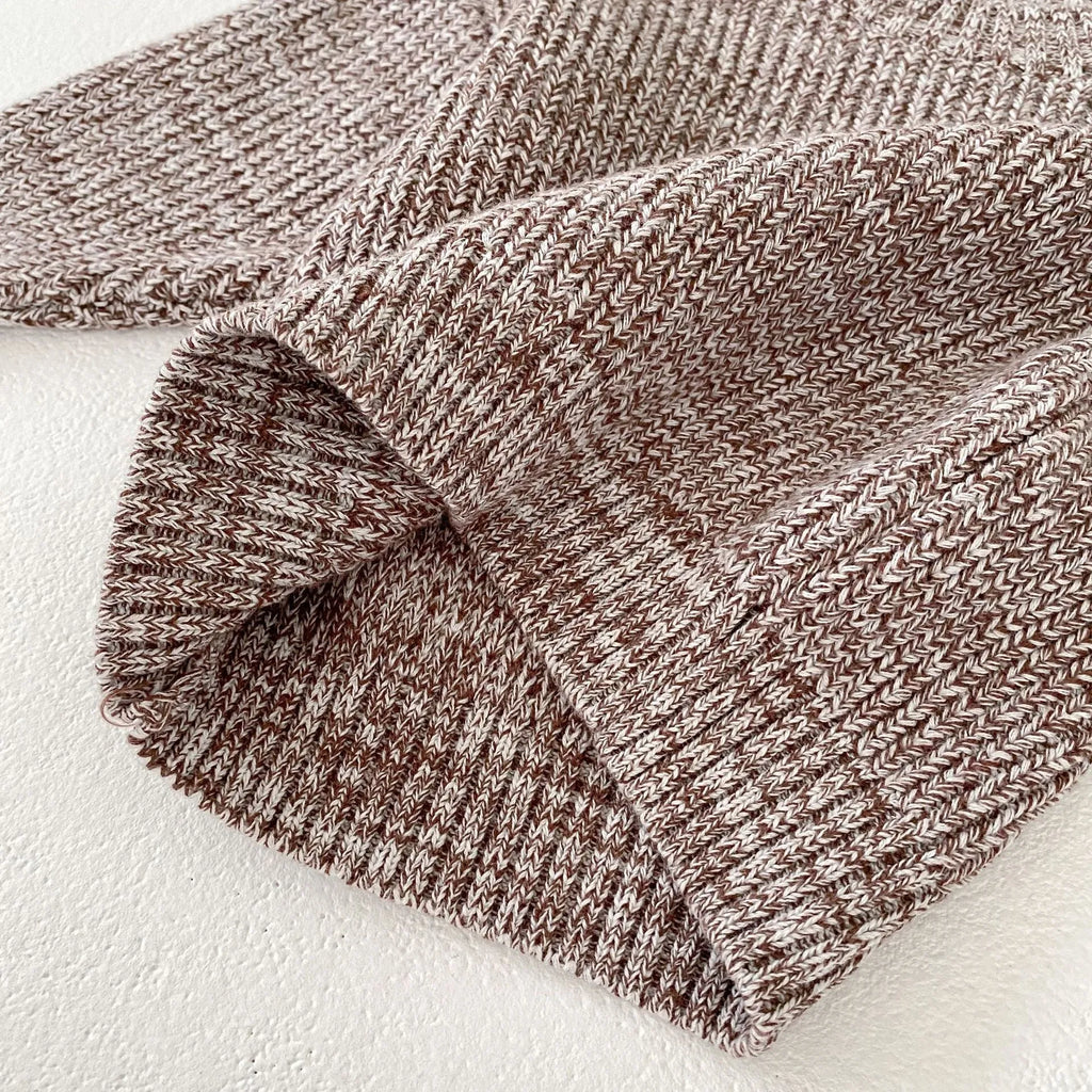 Dark brown knitted three-piece set for infant girl with fur ball hat, blouse, and shorts.