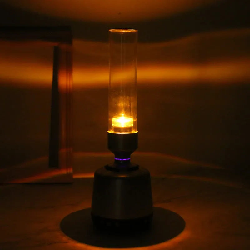 White silver cylindrical candlelight Bluetooth speaker night light on a surface.