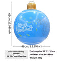 Large red inflatable Christmas ball with snowflake design and flashing lights in a garden setting.